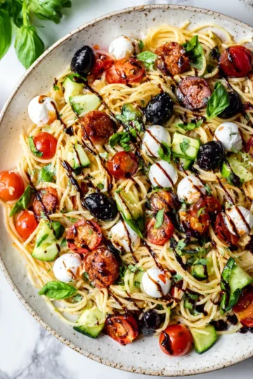 Ensalada de pasta italiana fresca con chorizo, mozzarella y verduras coloridas, ideal para el verano y compartir en reuniones.
