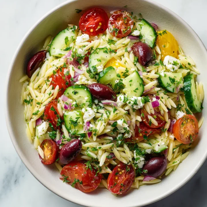 Ensalada fresca de orégano con orzo, vegetales y queso feta, ideal para el verano y picnics. Sabor mediterráneo en cada bocado.