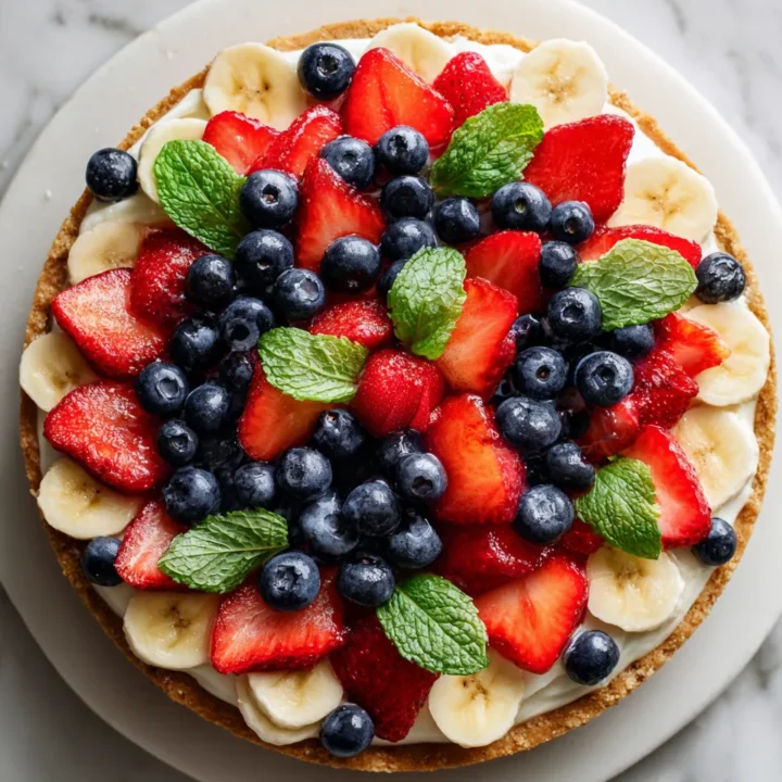 Pizza de frutas con queso crema, ideal para celebraciones veraniegas con colores vibrantes y sabores frescos.